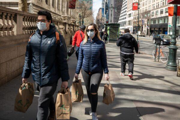 People carry groceries while wearing masks and gloves in New York City on March 14, 2020. (Apu Gomes/AFP via Getty Images)
