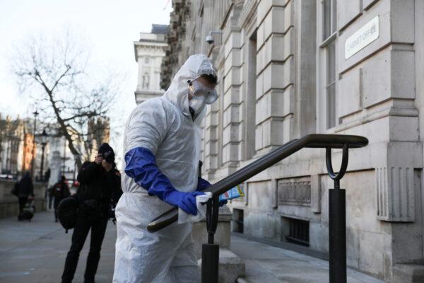A man in a protective suit cleans a handrail as the number of coronavirus cases (COVID-19) grows around the world, in London, Britain, on March 16, 2020. (Simon Dawson/Reuters)