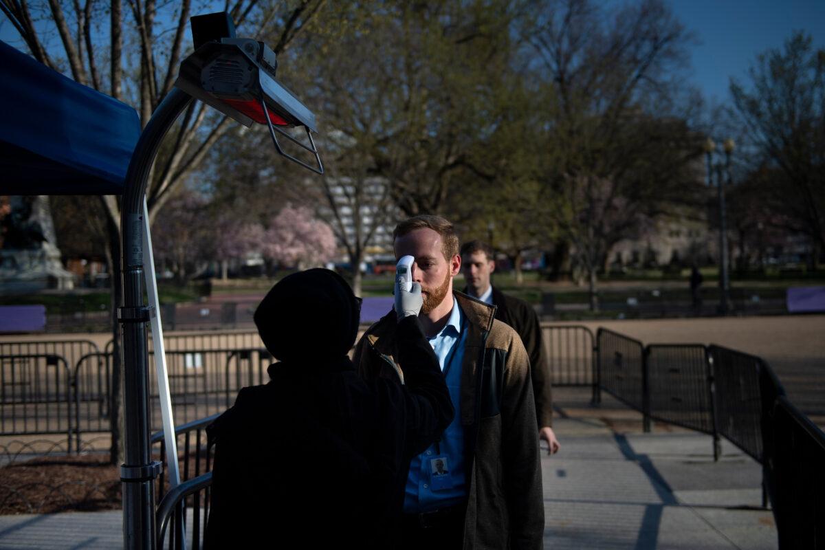 People's temperatures are checked outside a security checkpoint as they enter the White House in Washington on March 16, 2020. (Brendan Smialowski/AFP via Getty Images)