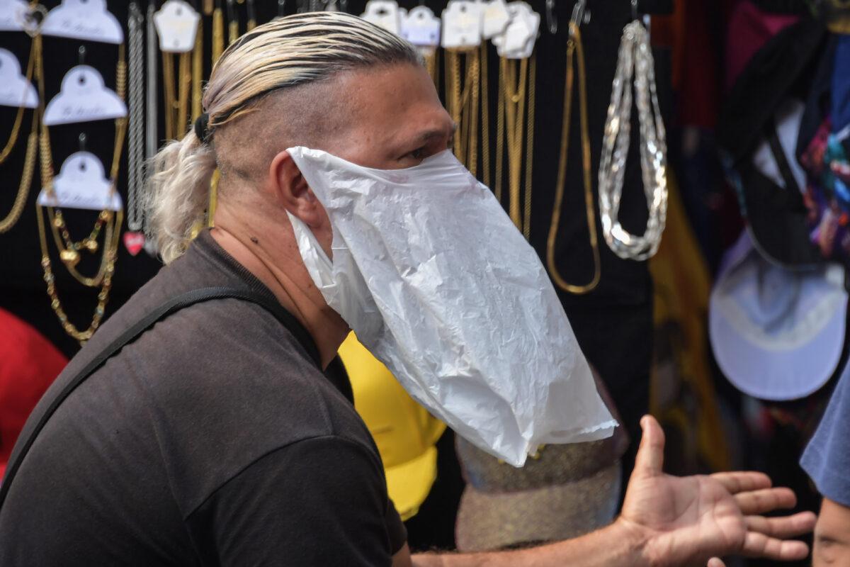 A street vendor wears a plastic bag as a preventive measure against the spread of the new coronavirus in downtown Sao Paulo, Brazil, on March 16, 2020. (Nelson Almeida/AFP via Getty Images)