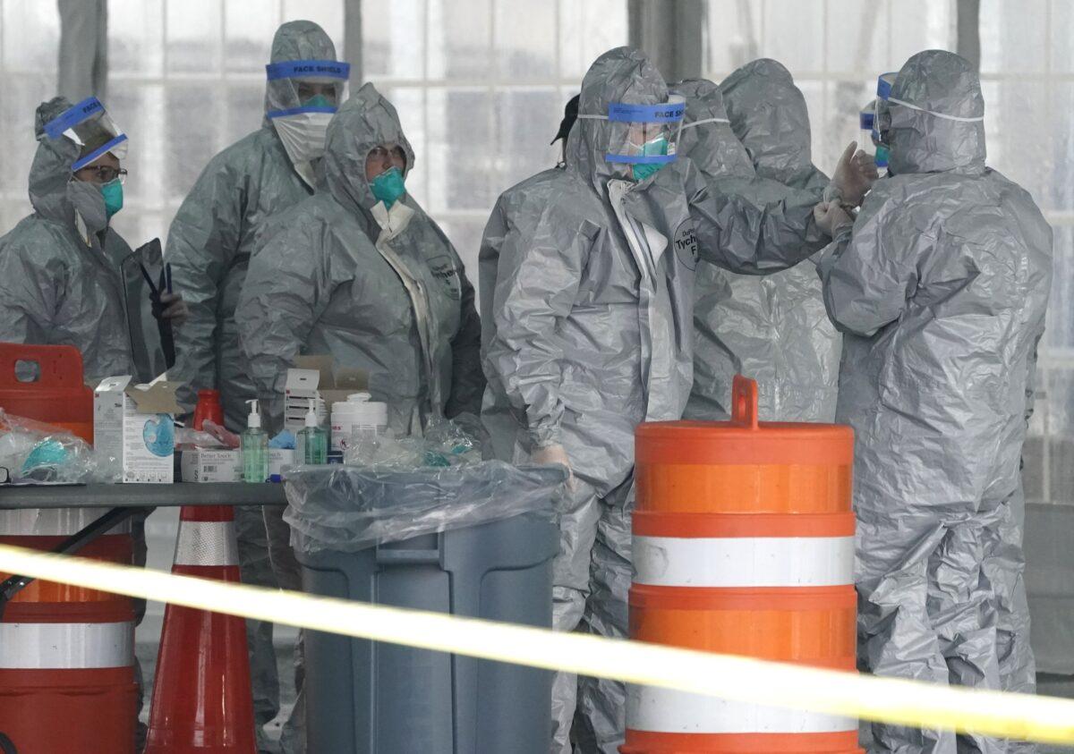 Workers in protective suits wait for people to be tested for Coronavirus (COVID-19) as they arrive by car at the state's first drive through COVID-19 Mobile Testing Center at Glen Island Park in New Rochelle, New York March 13, 2020. (Timothy A. Clary/AFP via Getty Images)