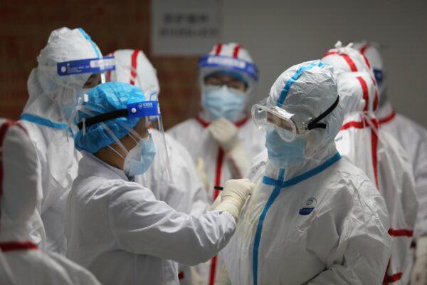 Medical staff write messages on their protective suits before attending to COVID-19 patients at the Red Cross Hospital in Wuhan, China, on March 16, 2020. (STR/AFP via Getty Images)
