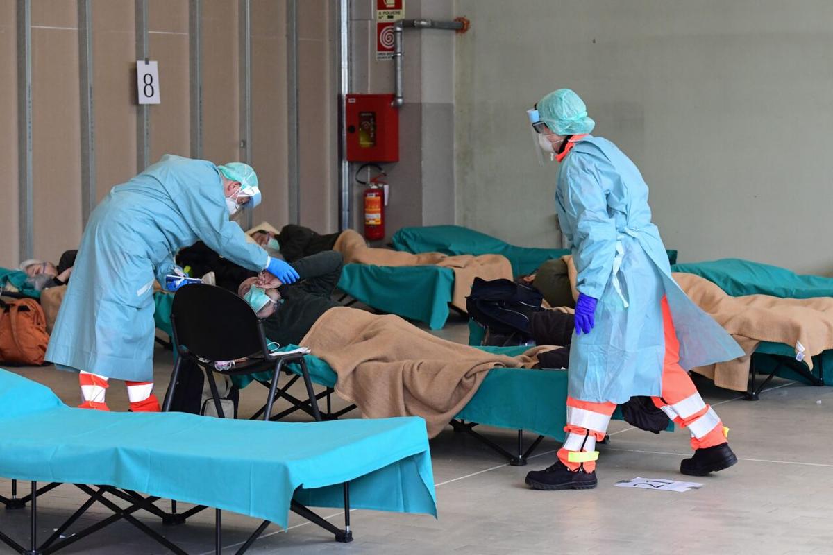 Hospital employees wearing protective masks and gear tend to a patient at a temporary emergency structure set up outside the accident and emergency department at the Brescia Hospital in Lombardy, Italy, on March 13, 2020. (Miguel Medina/ AFP)
