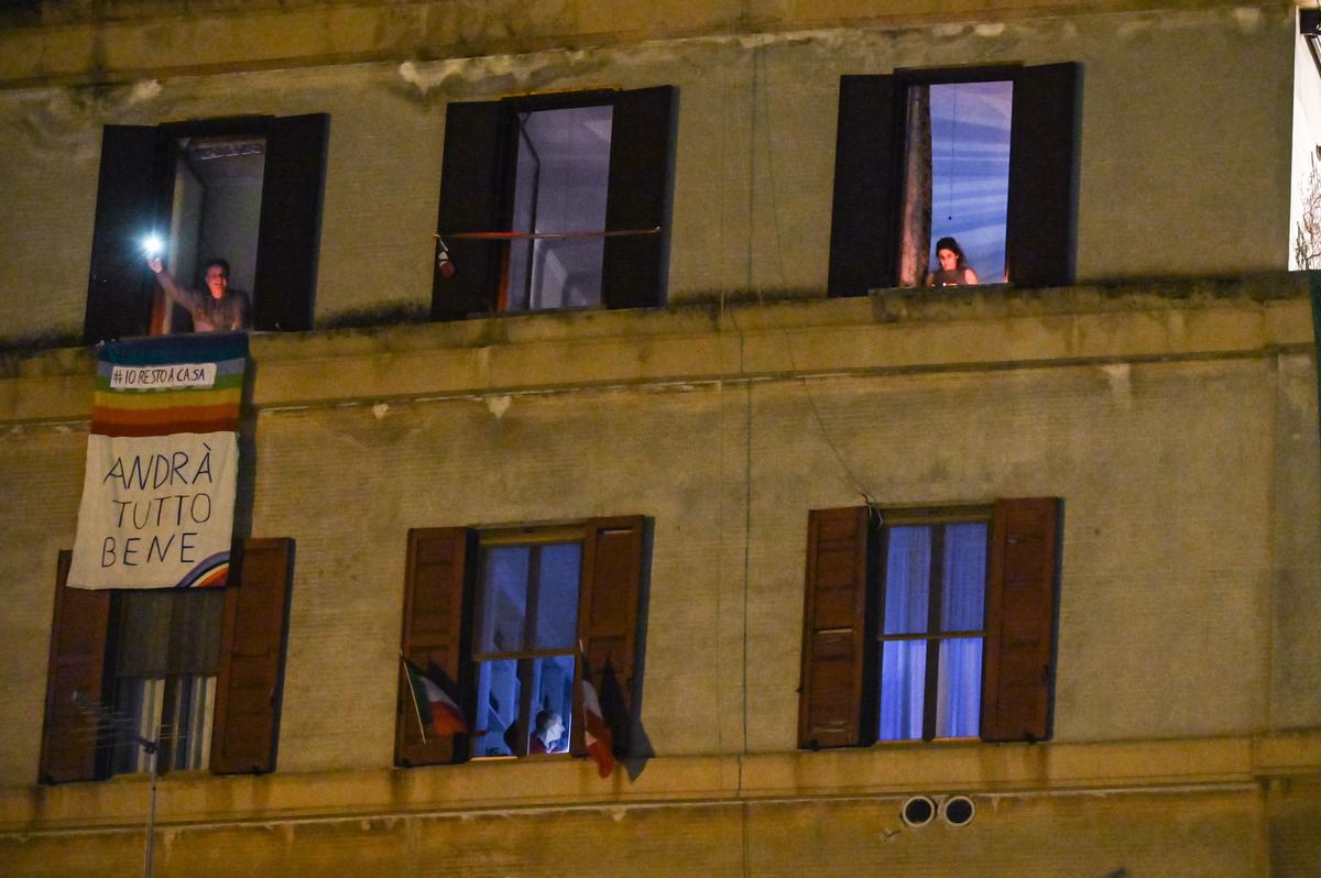 People brandish lights from their balconies during a lockdown flash mob, "Italia Patria Nostra" ("Italy Our Country") in Rome's Garbatella district on March 15, 2020. (©Getty Images | <a href="https://www.gettyimages.com/detail/news-photo/people-hold-lights-candles-flashlights-or-smartphoness-news-photo/1207242636?adppopup=true">ANDREAS SOLARO</a>)