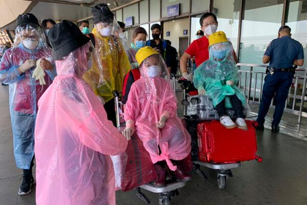 A Chinese family covered with plastic bags as a precautionary measure against the new coronavirus walk at the departure level of Manila's International Airport, Philippines, on March 18, 2020. (Joeal Calupitan/AP Photo)