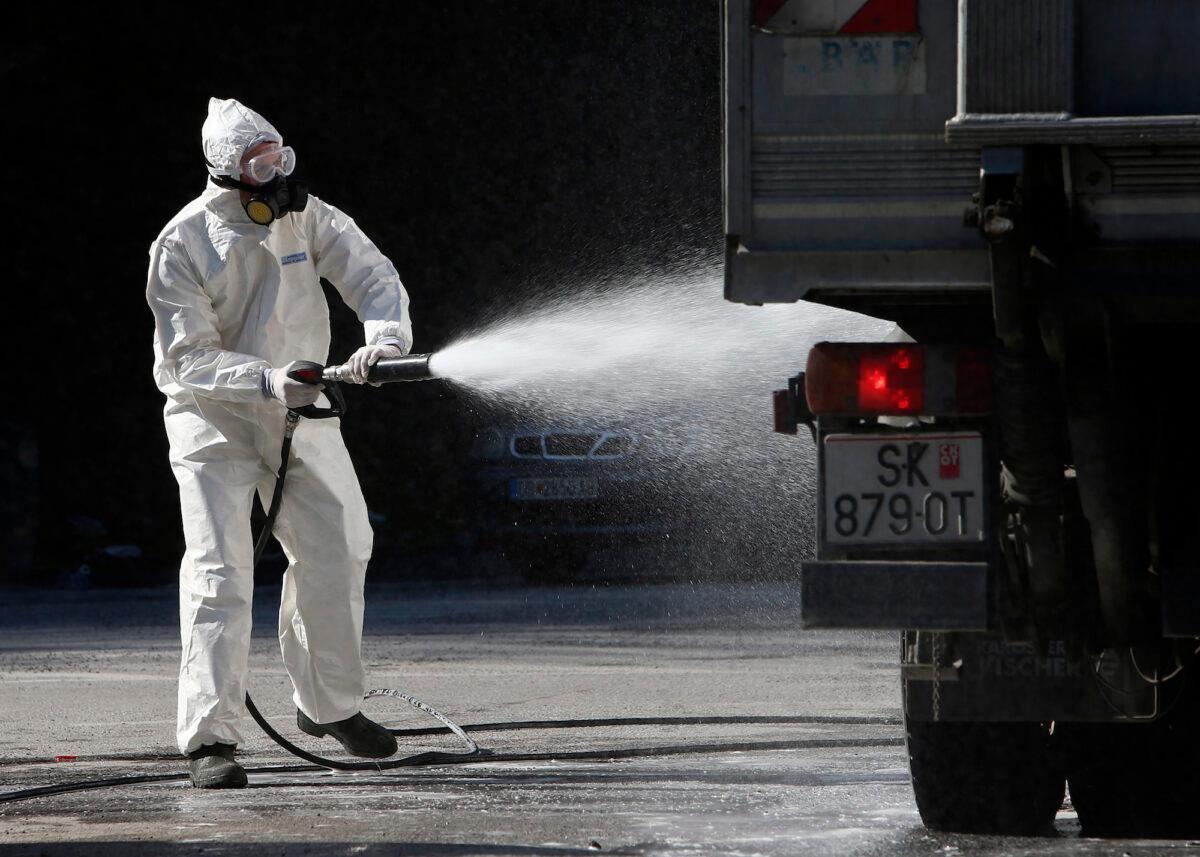 A worker wearing protective gear sprays disinfectant on a truck before entering an area infected with COVID-19 in North Macedonia on March 18, 2020. (Baris Grdanoski/AP Photo)