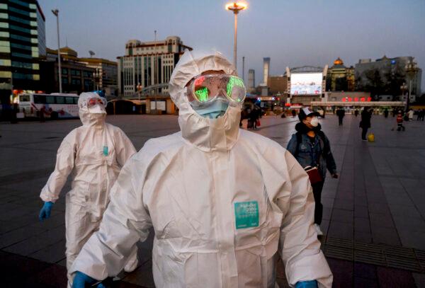 Two persons wearing protective masks and suits arrive at the Beijing Railway Station on March 13, 2020. (Kevin Frayer/Getty Images)