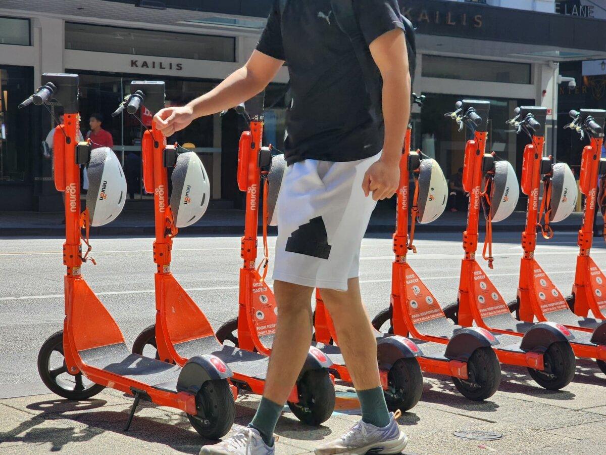 A man walks past a row of electric scooters for hire in Perth, Western Australia, on March 18, 2024. (Susan Mortimer/The Epoch Times)