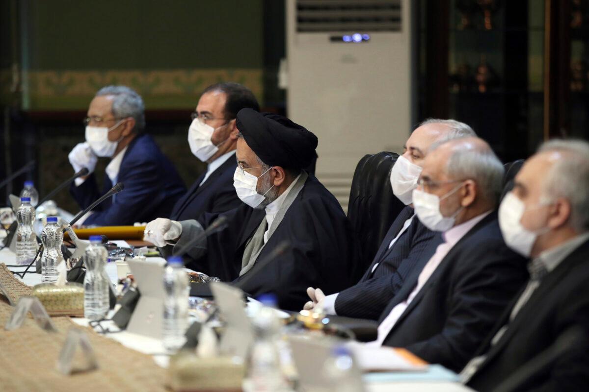 In this photo released by the official website of the Office of the Iranian Presidency, cabinet members wearing face masks and gloves attend their meeting in Tehran, Iran, on March 18, 2020. (Office of the Iranian Presidency via AP)