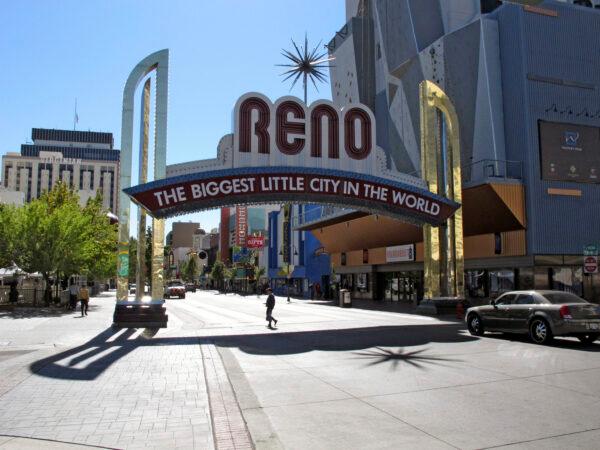 Pedestrians pass beneath the Reno arch as traffic passes on Virginia Street in downtown Reno, Nev. on March 20, 2020. (AP Photo/Scott Sonner, File)