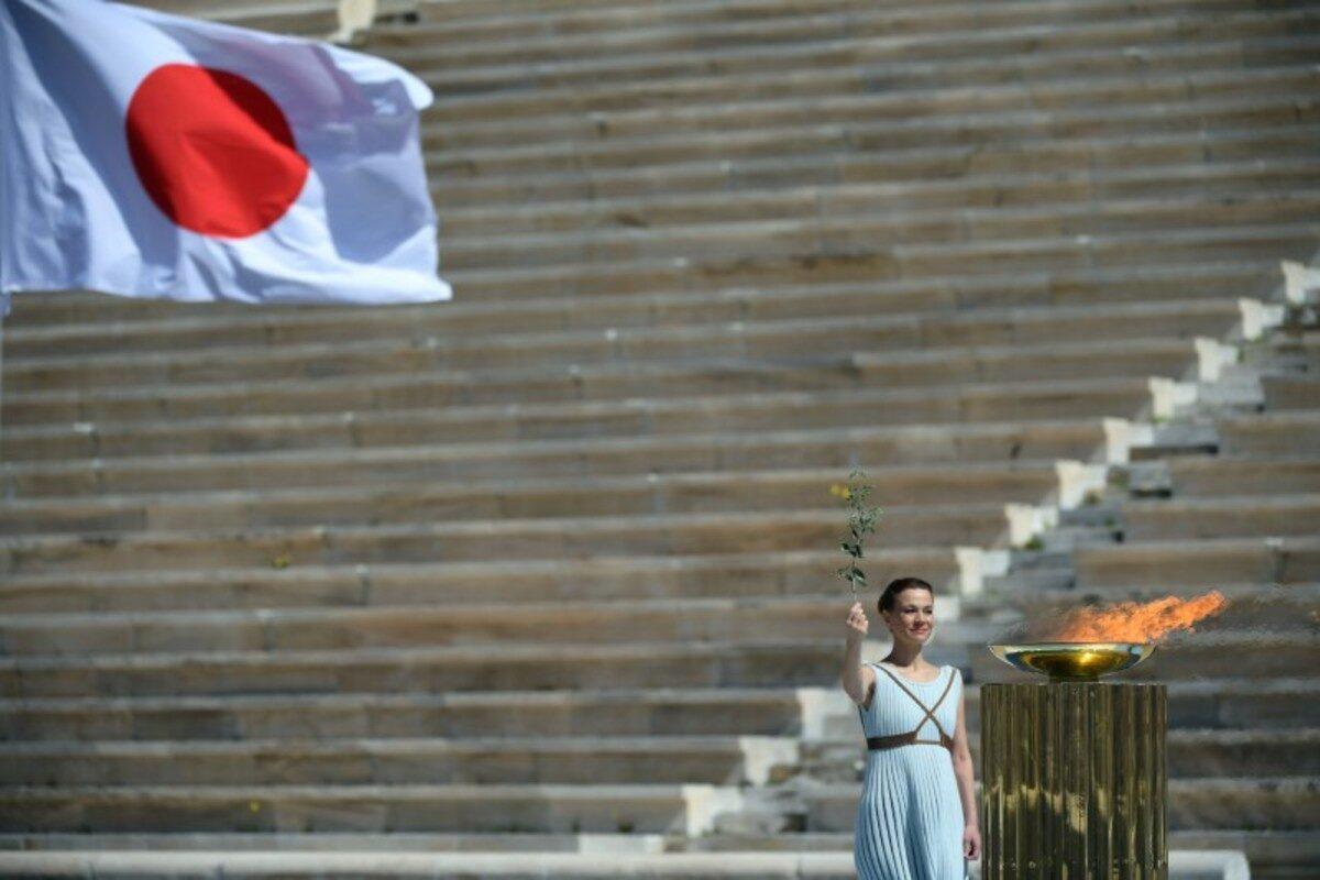 A performer stands next to the Olympic flame during the Olympic flame handover ceremony for the 2020 Tokyo Summer Olympics, in Panathenaic Stadium, Athens, Greece, on March 19, 2020. (Aris Messinis/Pool via Reuters)