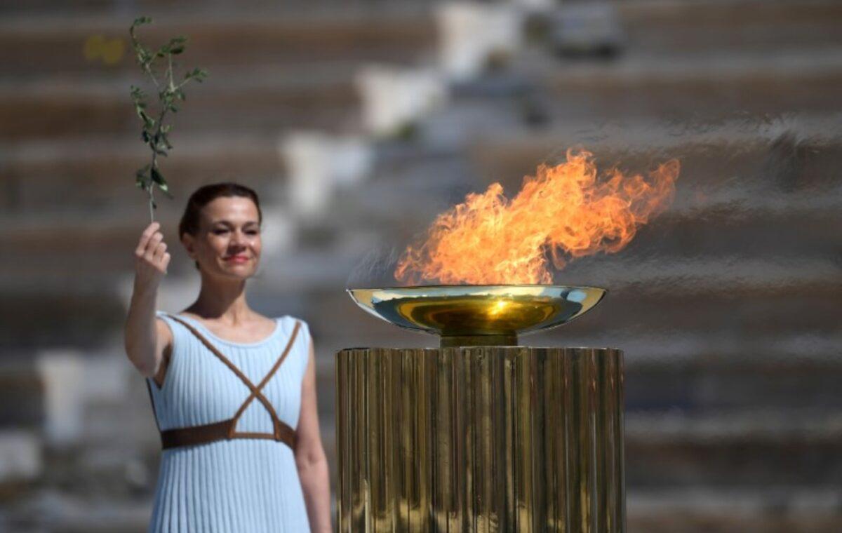 An athlete lights the Olympic torch during the Olympic flame handover ceremony for the 2020 Tokyo Summer Olympics, in Panathenaic Stadium, Athens, Greece, on March 19, 2020. (Aris Messinis/Pool via Reuters)