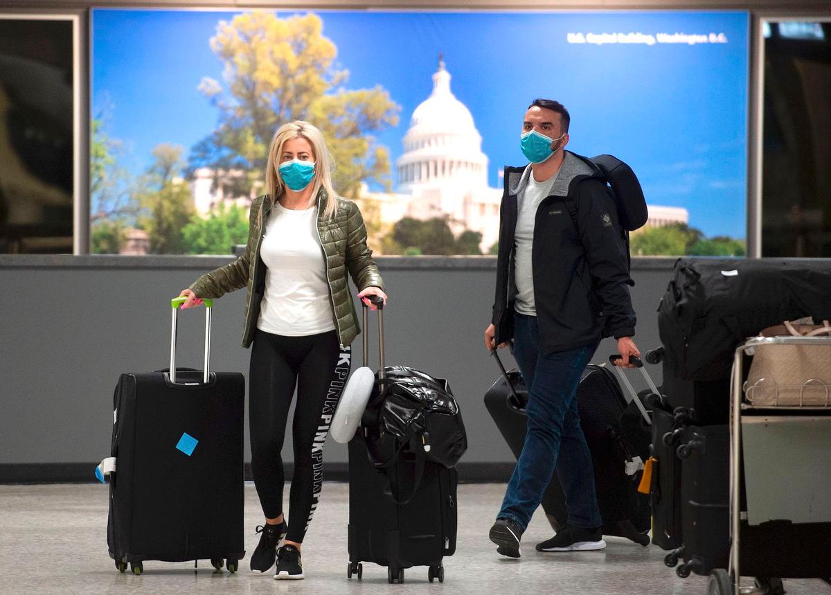 Passengers wear masks as they arrive at Dulles International airport in Dulles, Virginia, on March 17, 2020. (Andrew Caballero-Reynolds/AFP via Getty Images)