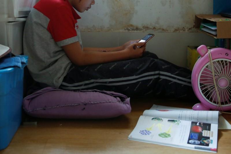 Secondary school student Wendy attends an online class with a smartphone at home during the novel coronavirus disease (COVID-19) outbreak, in Hong Kong, China, on March 16, 2020. (Tyrone Siu/Reuters)