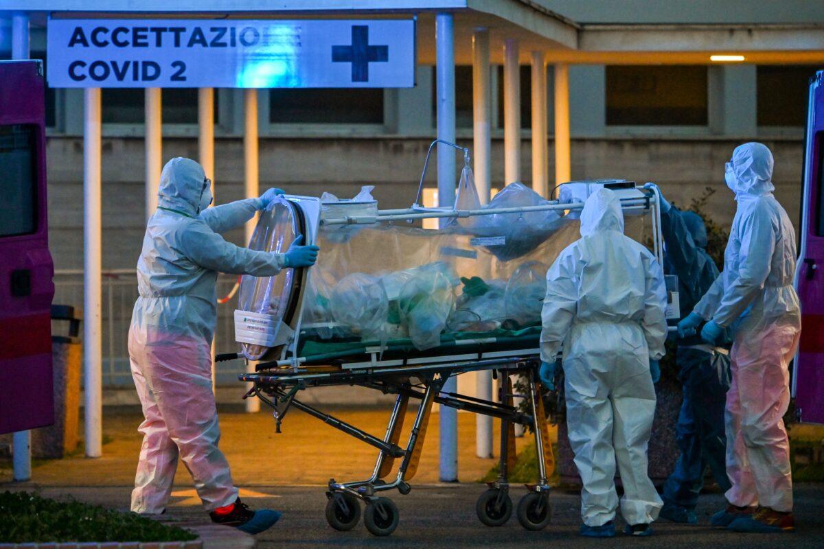 Medical workers in overalls stretch a patient under intensive care into the newly built Columbus Covid 2 temporary hospital to fight the new coronavirus infection, at the Gemelli hospital in Rome, on March 16, 2020. (Andreas Solaro /AFP via Getty Images)
