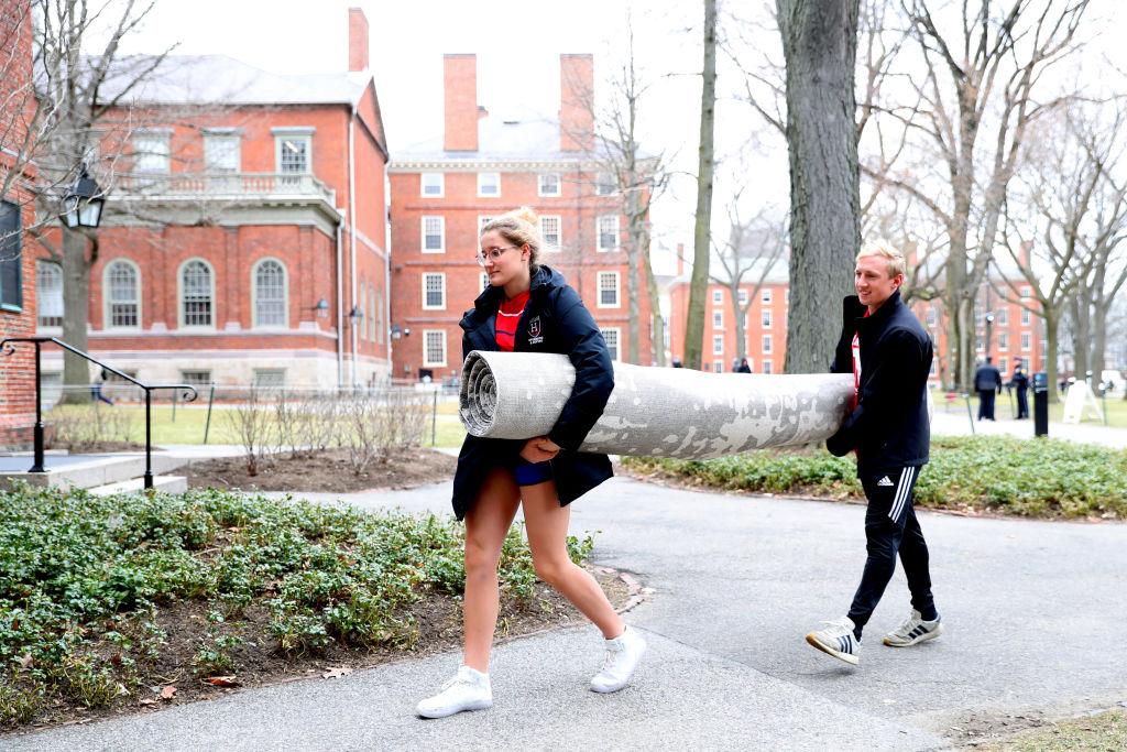 Sophomore Sophie Butte helps freshman Alex Petty move his rug across Harvard Yard on the campus of Harvard University in Cambridge, Mass., on March 12, 2020. (Maddie Meyer/Getty Images)