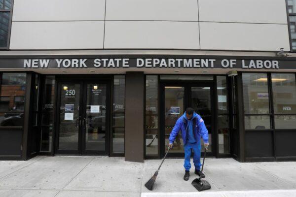 A person sweeps outside the New York State Department of Labor offices, which closed to the public due to the COVID-19 outbreak in Brooklyn, New York, on March 20, 2020. (Andrew Kelly/Reuters)