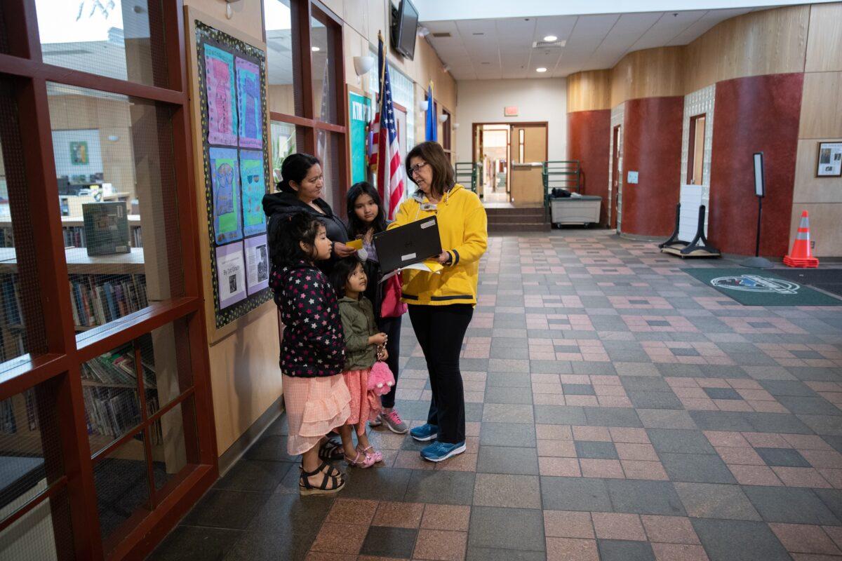 Bilingual teacher Maria Sanislo (R) explains a Google Chromebook to a family at KT Murphy Elementary School on March 17, 2020 in Stamford, Connecticut. Stamford Public Schools closed last week to help slow the spread of COVID-19, and students are now "distance learning" from home. (John Moore/Getty Images)