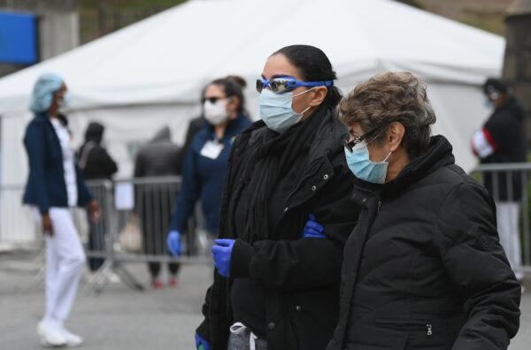 People wearing masks and goggles pass by a COVID-19 screening tent outside the Brooklyn Hospital Center in the Brooklyn borough of New York City on March 20, 2020. (Angela Weiss/AFP via Getty Images)
