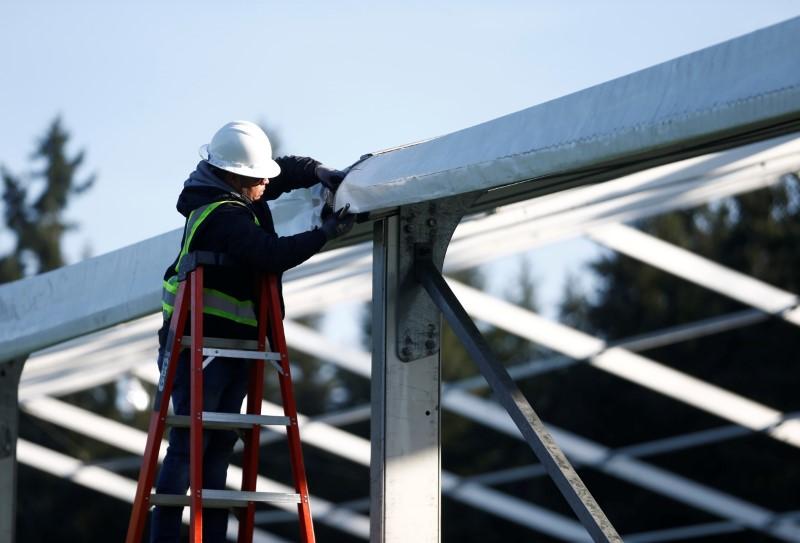 A worker puts up siding for a 200-bed temporary field hospital for people exposed to, at risk of exposure, or becoming ill with the CCP virus at the Shoreline Soccer Field during the outbreak of COVID-19 in Shoreline, Washington on March 19, 2020. (Lindsey Wasson/Reuters)