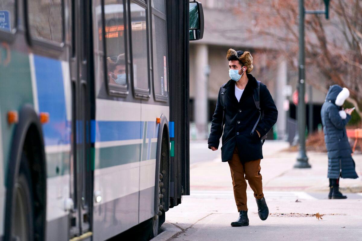 A man in a mask boards a bus on campus at Western University in London, Ontario on March 13, 2020. (Geoff Robins/AFP via Getty Images)