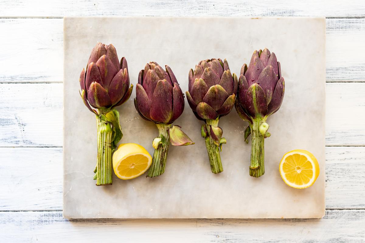 Prepare your artichokes and a halved lemon, to squeeze into a bowl of water.