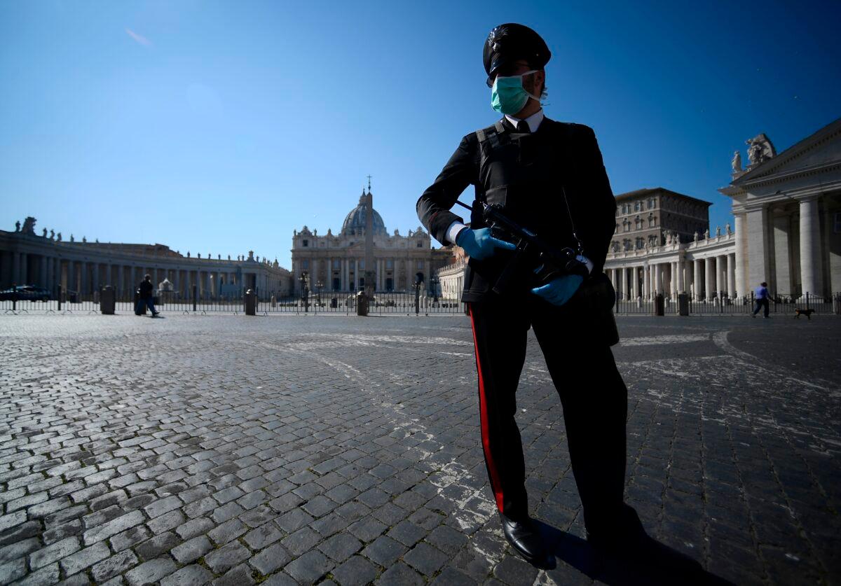 An armed Carabinieri police officer, wearing a face mask, patrols a closed and deserted St. Peter's Square in the Vatican on March 19, 2020, during the lockdown within the new coronavirus pandemic. (Filippo Monteforte/AFP via Getty Images)