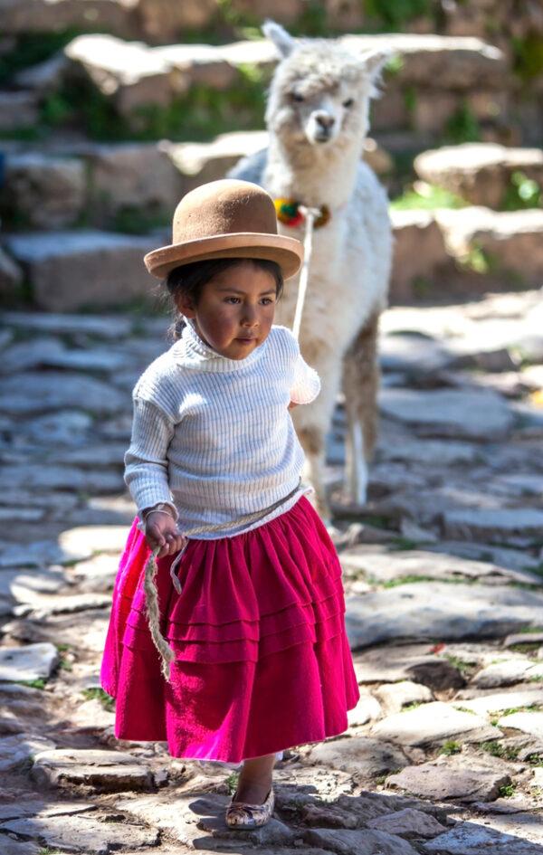 A young girl leads a llama on Sun Island, Lake Titicaca. (Thomas Wyness/SHUTTERSTOCK)