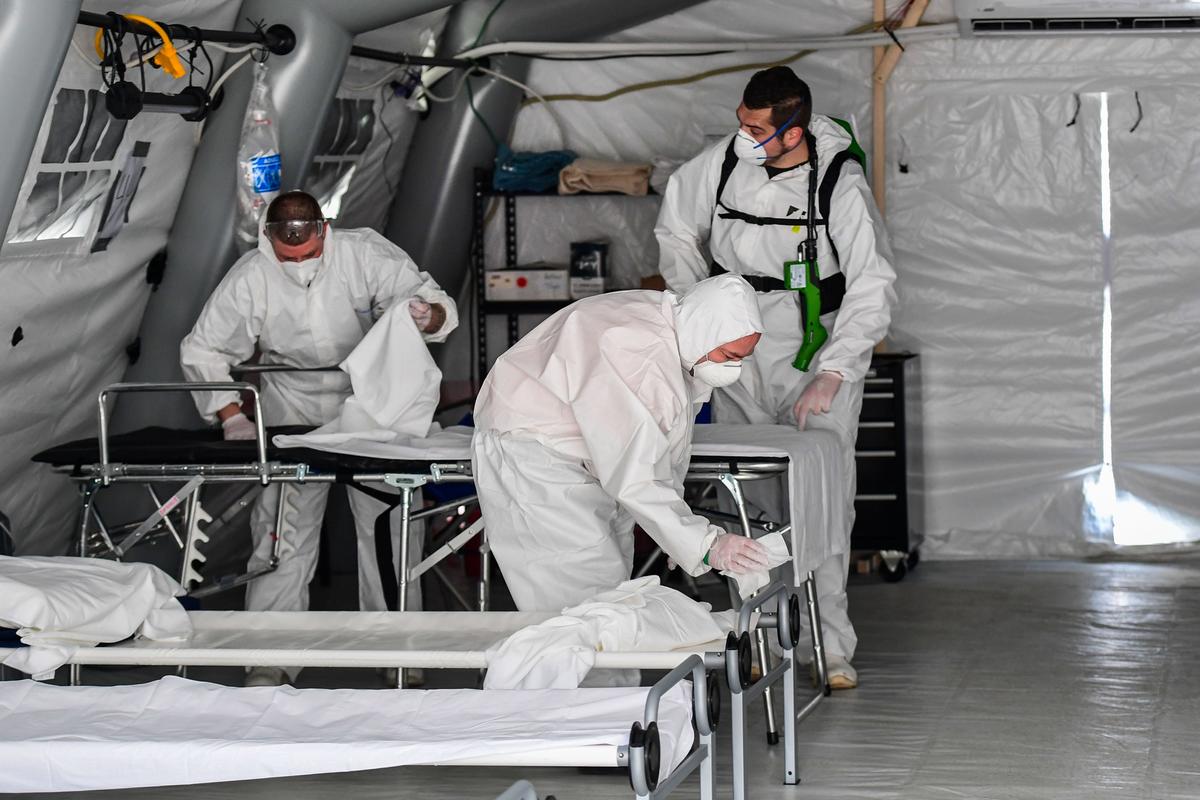 A view taken on March 20, 2020, in Cremona, southeast of Milan, shows cleaning personnel in protective gear disinfecting patients' beds in one of the tents from a newly operative field hospital for coronavirus patients. (©Getty Images | <a href="https://www.gettyimages.com/detail/news-photo/view-taken-on-march-20-2020-in-cremona-southeast-of-milan-news-photo/1207749367?adppopup=true">MIGUEL MEDINA</a>)