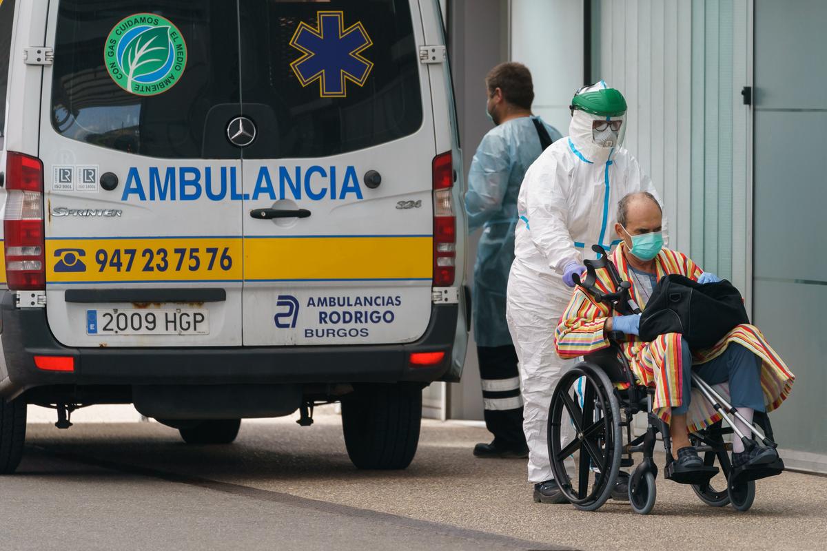 A health worker in a protective suit pushes a man on a wheelchair into the Burgos Hospital in Spain on March 23, 2020. (Cesar Manso/AFP/Getty Images)