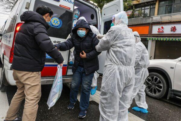 A patient assisted by medical staff members wearing protective clothing to help stop the spread of a deadly virus which began in the city, as he gets off an ambulance in Wuhan in China's central Hubei province, on Jan. 26, 2020. (STR/AFP via Getty Images)