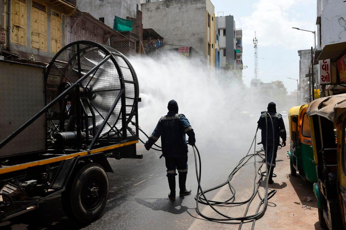 Firefighters from Ahmedabad Fire and Emergency Services spray disinfectant along a street during Gujarat's government-imposed lockdown as a preventive measure against the COVID-19 coronavirus, in Ahmedabad on March 24, 2020. (Sam Panthaky/AFP via Getty Images)