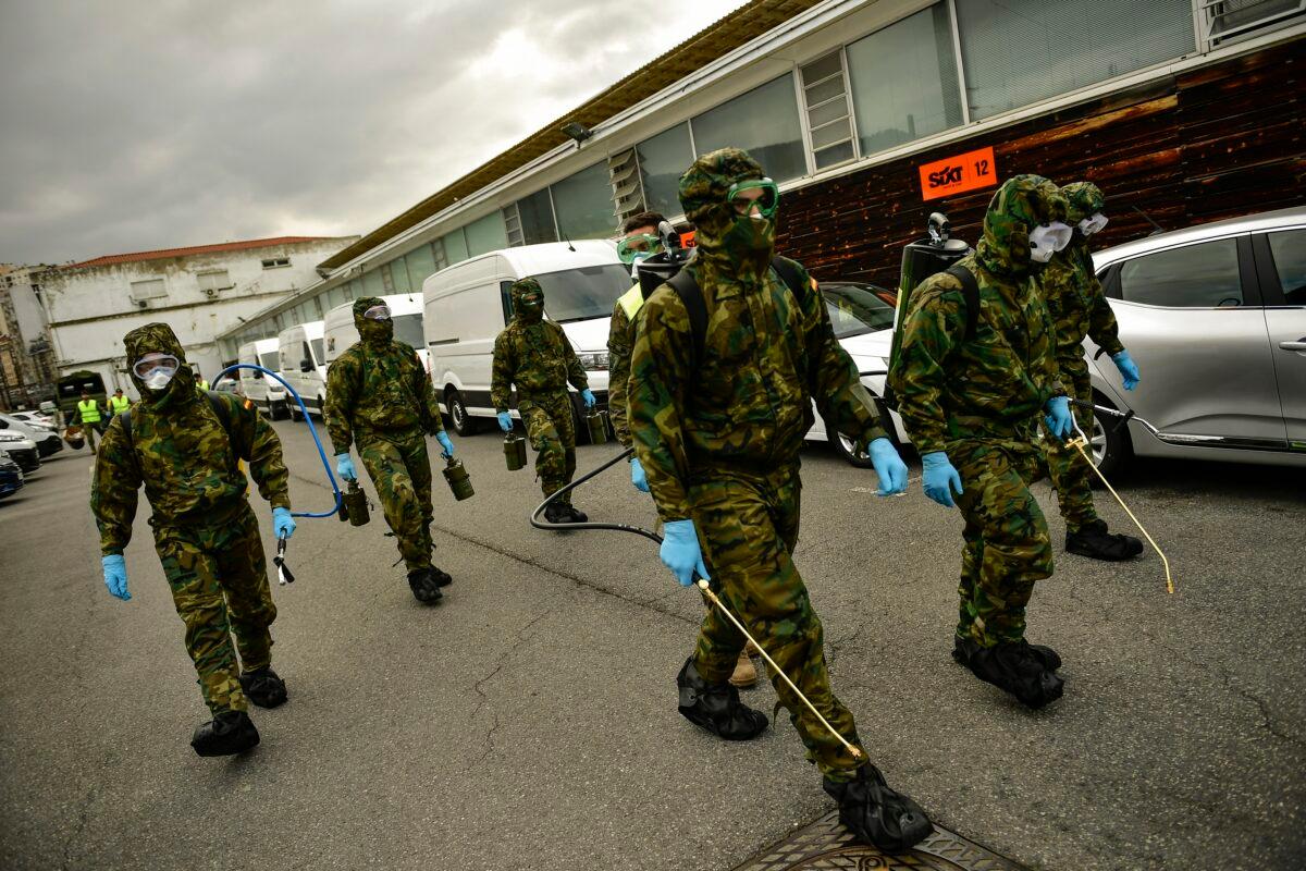 Member of Military Emergency Unit walk with special equipment to disinfect areas to prevent the spread of the coronavirus, arrive at Abando train station, in Bilbao, northern Spain on March 23, 2020. (Alvaro Barrientos/AP Photo)
