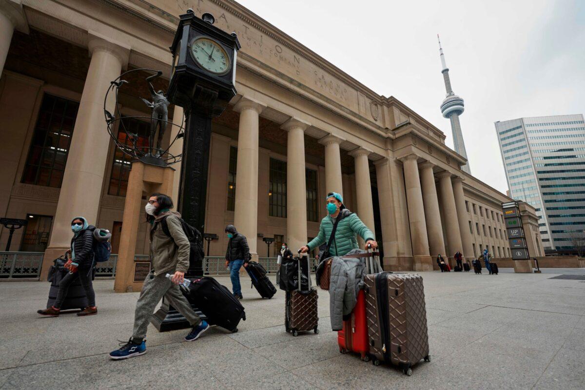 Travellers in masks leave Union Station in Toronto, Ontario, Canada, on March 24, 2020. (Photo by Geoff Robins / AFP via Getty Images)