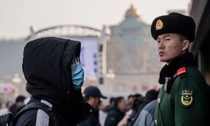 A man wearing a protective mask arrives at Beijing railway station next to a paramilitary police officer (R) as he heads home for the Lunar New Year on Jan. 21, 2020. (Nicolas Asfouri/AFP via Getty Images)