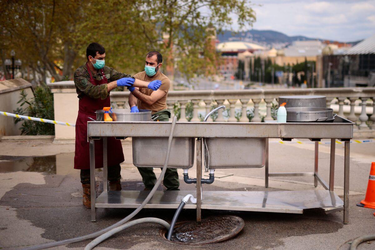 Spanish soldiers wash their hands outside a temporary hospital for vulnerable people set up at the Fira Barcelona Montjuic centre in Barcelona on March 25, 2020. (Pau Barrena/AFP via Getty Images)