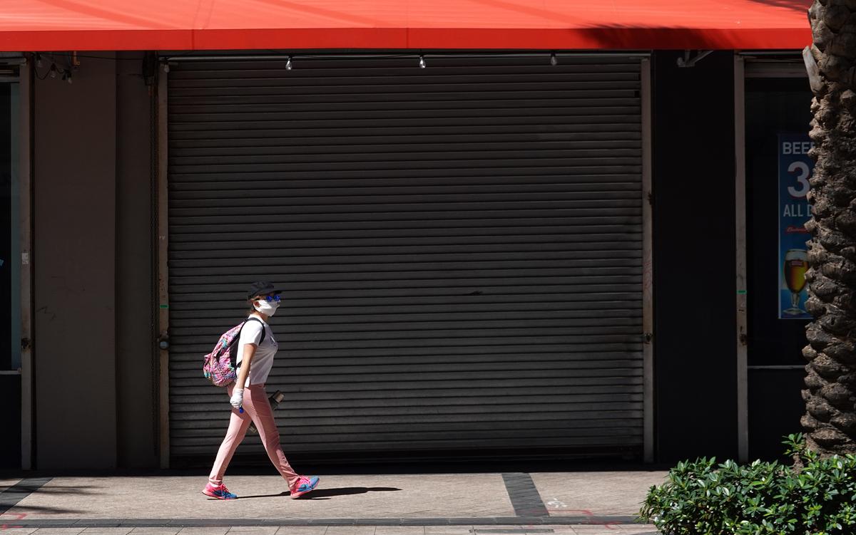 A pedestrian wearing a protective mask walks down an empty sidewalk as large numbers of people stay home in an effort to contain the coronavirus pandemic in Miami, Florida, on March 24, 2020. (Joe Raedle/Getty Images)