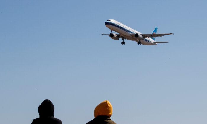  People watch a plane of China Southern Airlines land at Beijing Capital International in Beijing as the country is hit by an outbreak of the CCP Virus, China, March 13, 2020. (Reuters/Thomas Peter)