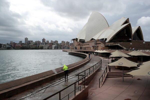 A worker cleans the waterfront area of the Sydney Opera House, in the wake of New South Wales implementing measures shutting down non-essential businesses and moving toward harsh penalties to enforce self-isolation as the spread of coronavirus disease (COVID-19) reached what the state's premier calls a "critical stage" in Australia, on March 26, 2020. (Loren Elliott/Reuters)