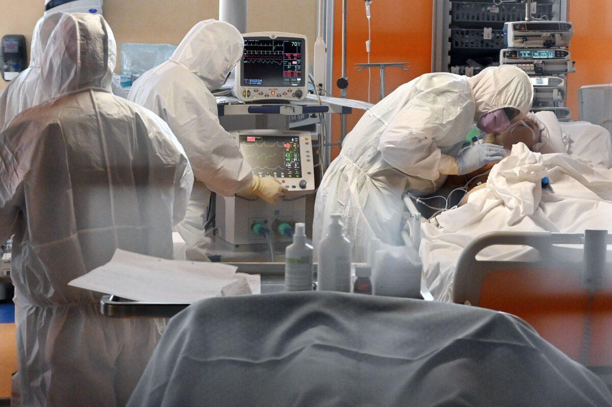 A medical worker in protective gear (R) tends to a patient at the new COVID 3 level intensive care unit for COVID-19 cases at the Casal Palocco hospital near Rome, Italy, on March 24, 2020. (Alberto Pizzoli/ AFP via Getty Images)