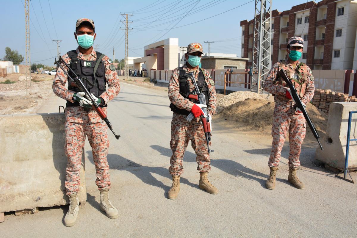 Soldiers guard a quarantine facility for people returning from Iran via the Pakistan-Iran border town of Taftan in Sukkur, southern Sindh Province. (©Getty Images | <a href="https://www.gettyimages.com/detail/news-photo/soldiers-wearing-facemasks-stand-guard-on-road-leading-to-a-news-photo/1207461018?adppopup=true">SHAHID ALI</a>)