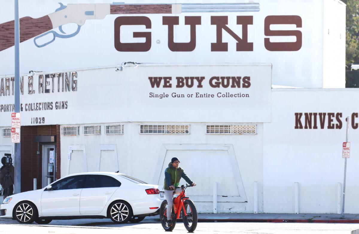 A cyclist rides past the Martin B. Retting, Inc. guns store as the CCP Virus pandemic continues in Culver City, California on March 24, 2020. (Mario Tama/Getty Images)