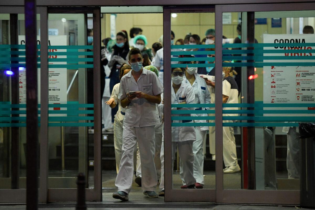 Healthcare workers dealing with the CCP virus crisis stand at the entrance of the Fundacion Jimenez Diaz hospital in Madrid on March 25, 2020. (Oscar Del Pozo/AFP via Getty Images)