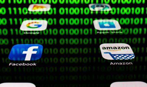 The apps for Google, Amazon, Facebook, Apple with the reflection of binary code are displayed on a tablet screen in Paris on April 20, 2018. (Lionel Bonaventure/AFP via Getty Images)