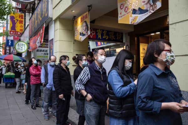 People wait in line at a pharmacy to pick up masks pre-ordered online, in Taipei, Taiwan, on March 18, 2020. (Paula Bronstein/Getty Images )