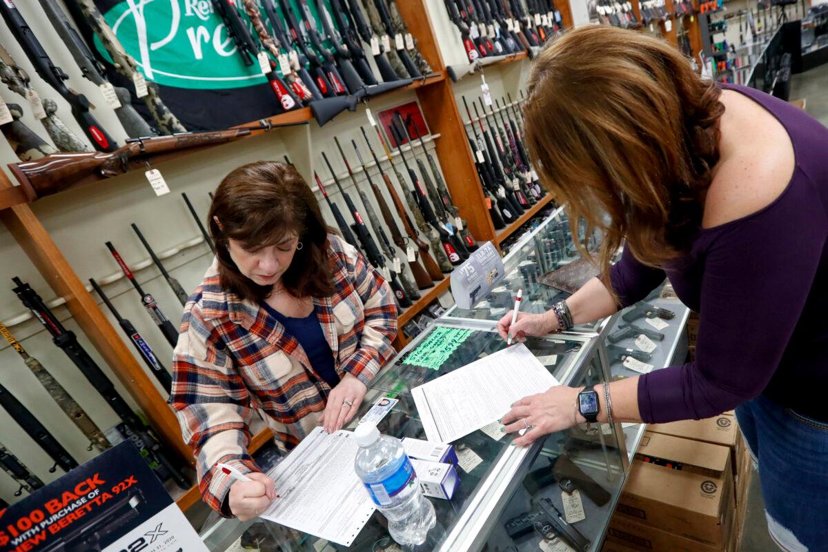 Andrea Schry, right, fills out the buyer part of legal forms to buy a handgun as shop worker Missy Morosky fills out the vendors parts after Dukes Sport Shop reopened in New Castle, Pa., on March 25, 2020. (Keith Srakocic/AP Photo)