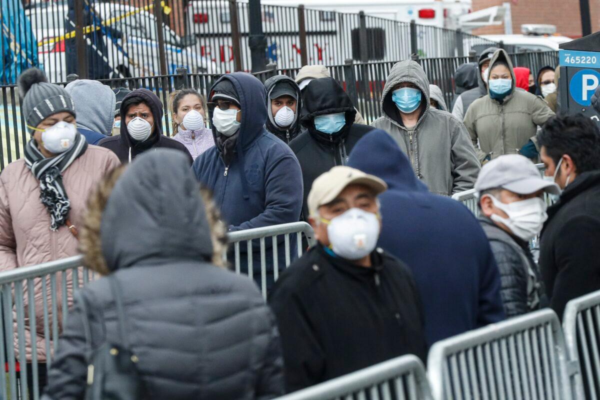 Patients wear personal protective equipment while maintaining social distancing as they wait in line for a COVID-19 test at Elmhurst Hospital Center in New York City on March 25, 2020. (John Minchillo/AP Photo)
