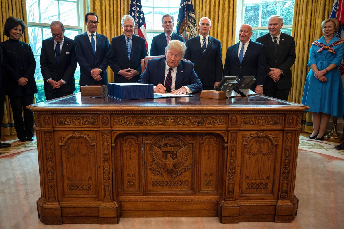 President Donald Trump signs the CARES act, a $2.2 trillion rescue package to provide economic relief amid the CCP virus outbreak, at the Oval Office of the White House in Washington on March 27, 2020. (Jim Watson/AFP via Getty Images)