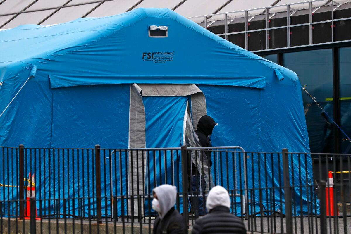 A person emerges from a tent set up in the driveway of the emergency entrance to Elmhurst Hospital Center in New York on March 28, 2020, as others wait in line to be tested for the CCP virus. The hospital is caring for a high number of CCP virus patients in the city. (Kathy Willens/AP Photo)