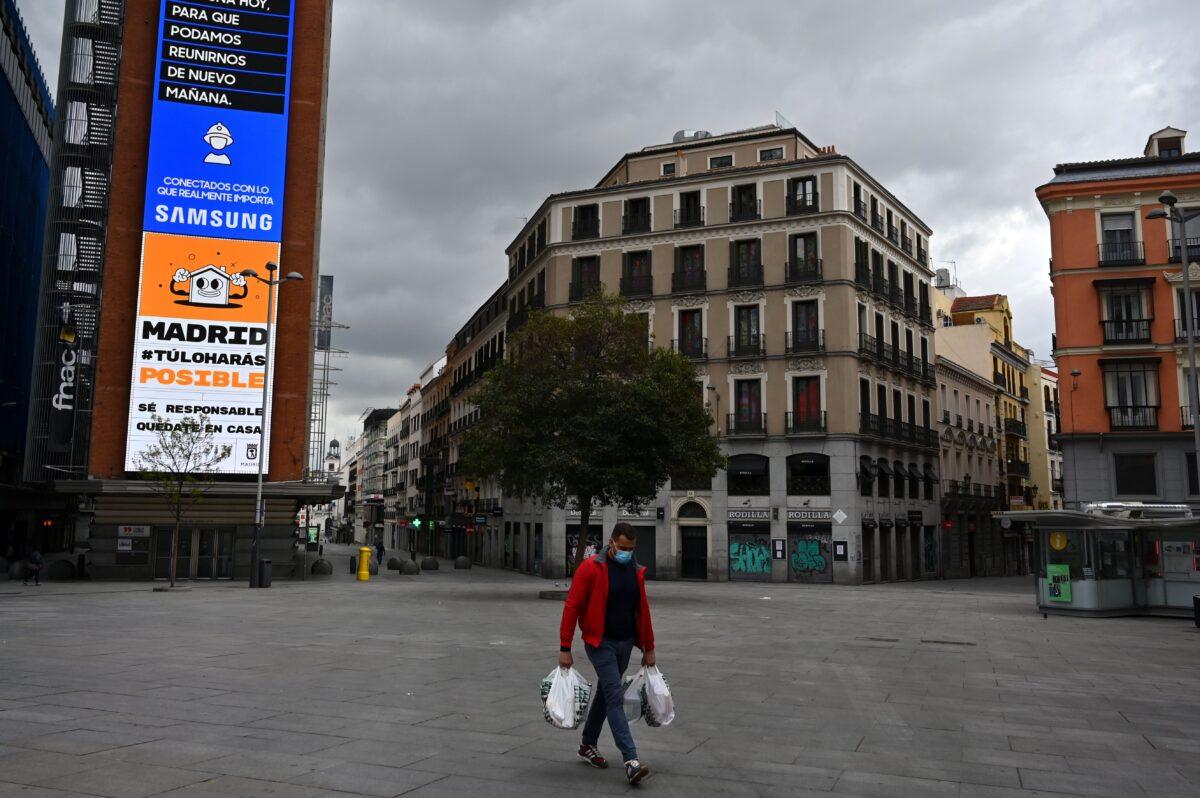 A man carrying grocery bags walks in a deserted street in Madrid on March 27, 2020. (Gabriel Bouys/AFP via Getty Images)